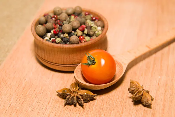 Tomates vermelhos em colher, pimenta e anis estrelado — Fotografia de Stock