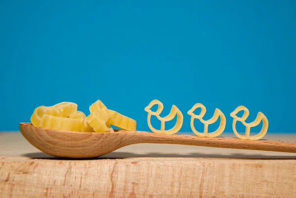 Pasta in the form of animals and a spoon on a blue background — Stock Photo, Image