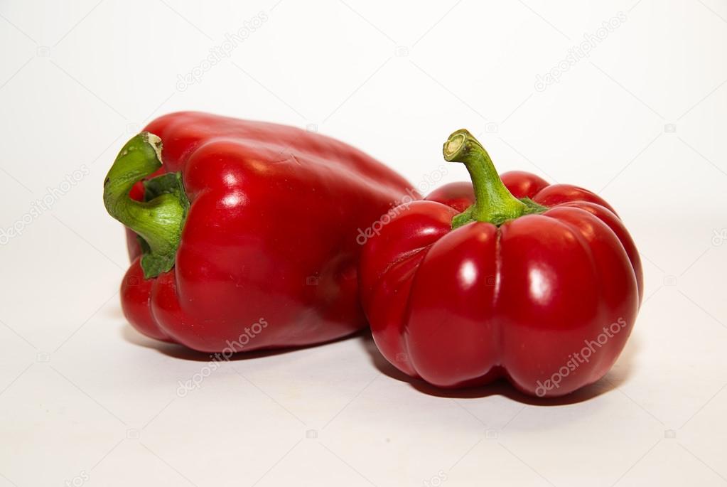Two ripe red peppers on over white