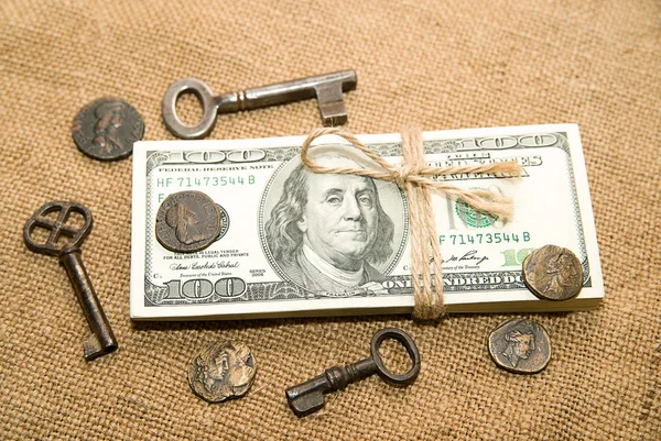 One pack of dollars, coins and keys on an old cloth — Stock Photo, Image