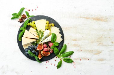 Tabakta çeşitli peynirler var. Parmesan peyniri, mavi peynir ve üzümlü ve incirli peynir. Antipasto. Üst görünüm.