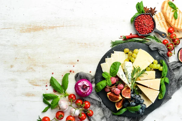 Assorted cheeses on a plate. Parmesan cheese, blue cheese and brie on a plate with grapes and figs. Antipasto. Top view.