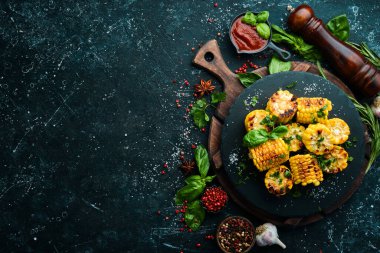 Yiyecekler. Siyah taş tabakta maydanozlu ve fesleğenli fırında mısır. Üst Manzara. Metnin için boş yer.