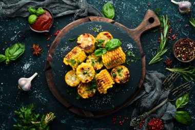 Yiyecekler. Siyah taş tabakta maydanozlu ve fesleğenli fırında mısır. Üst Manzara. Metnin için boş yer.