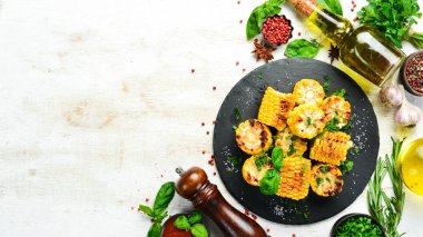 Yiyecekler. Siyah taş tabakta maydanozlu ve fesleğenli fırında mısır. Üst Manzara. Metnin için boş yer.