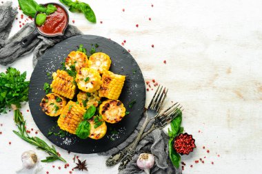 Yiyecekler. Siyah taş tabakta maydanozlu ve fesleğenli fırında mısır. Üst Manzara. Metnin için boş yer.