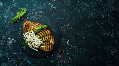 Yiyecekler. Fırında patlıcan, mavi peynirli ve fesleğenli siyah taş tabakta. Üst Manzara. Metnin için boş yer.