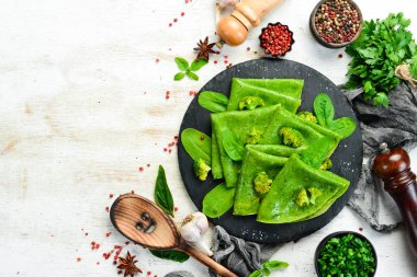 Vejetaryen yemeği. Siyah taş tabakta sebzeli yeşil ıspanaklı krep. Üst Manzara. Metnin için boş yer.