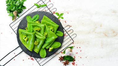 Vejetaryen yemeği. Siyah taş tabakta sebzeli yeşil ıspanaklı krep. Üst Manzara. Metnin için boş yer.