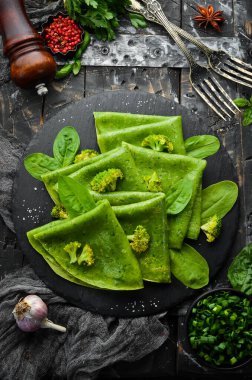 Vejetaryen yemeği. Siyah taş tabakta sebzeli yeşil ıspanaklı krep. Üst Manzara. Metnin için boş yer.