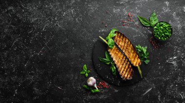 Siyah taş tabakta fesleğenli ızgara patlıcan. Üst Manzara. Metnin için boş yer.