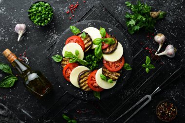 Fesleğenli Caprese salatası. Siyah taş tabakta domates, mozarella peyniri ve patlıcan. Üst Manzara. Metnin için boş yer.
