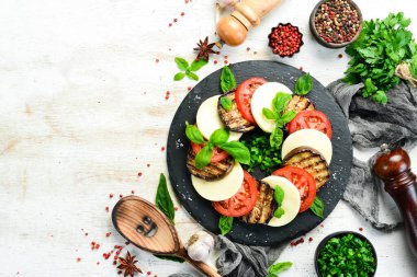 Fesleğenli Caprese salatası. Siyah taş tabakta domates, mozarella peyniri ve patlıcan. Üst Manzara. Metnin için boş yer.
