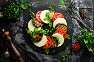 Fesleğenli Caprese salatası. Siyah taş tabakta domates, mozarella peyniri ve patlıcan. Üst Manzara. Metnin için boş yer.
