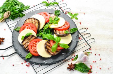 Fesleğenli Caprese salatası. Siyah taş tabakta domates, mozarella peyniri ve patlıcan. Üst Manzara. Metnin için boş yer.