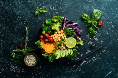 Vejetaryen Buda kasesi: Siyah taş tabakta nohut, brokoli, domates ve salatalık. Yiyecekler. Üst Manzara. Metnin için boş yer.