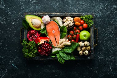 Gıda geçmişi: Bir dizi sağlıklı ve temiz yiyecek - sebze, meyve, balık, et, fındık ve sebze. Siyah taştan bir arka planda. Üst Manzara. Boş kopyalama alanı.