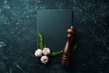Masa ayarı. Biberiye ve sarımsaklı siyah taş tabak. Üst Manzara. Boş kopyalama alanı.