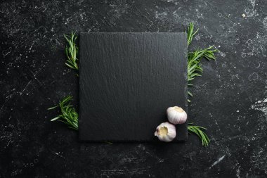 Masa ayarı. Biberiye ve sarımsaklı siyah taş tabak. Üst Manzara. Boş kopyalama alanı.