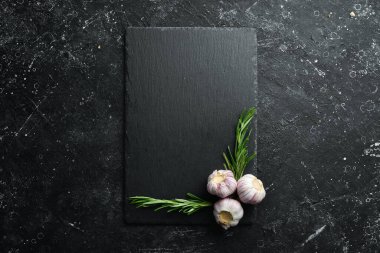 Masa ayarı. Biberiye ve sarımsaklı siyah taş tabak. Üst Manzara. Boş kopyalama alanı.
