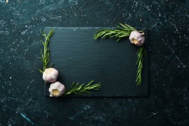 Masa ayarı. Biberiye ve sarımsaklı siyah taş tabak. Üst Manzara. Boş kopyalama alanı.