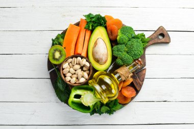 E vitamini bakımından zengin yiyecek seti: balkabağı, brokoli, kurutulmuş kayısı, maydanoz, avokado ve sebze. Üst Manzara. Kırsal biçim.