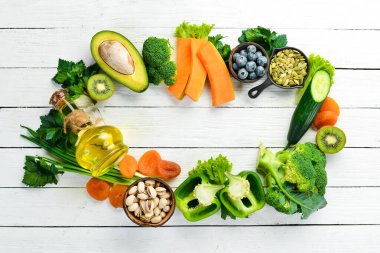 E vitamini bakımından zengin yiyecek seti: balkabağı, brokoli, kurutulmuş kayısı, maydanoz, avokado ve sebze. Üst Manzara. Kırsal biçim.