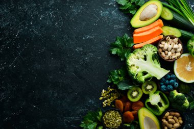 E vitamini bakımından zengin yiyecek seti: balkabağı, brokoli, kurutulmuş kayısı, maydanoz, avokado ve sebze. Üst Manzara. Kırsal biçim.