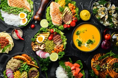 Yemek geçmişi: makarna, tavuk, balkabağı, salata, et, mantar, sebze. Siyah taştan bir arka planda. Üst Manzara. Metin için boş alan.