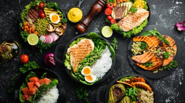 Yemek geçmişi: makarna, tavuk, balkabağı, salata, et, mantar, sebze. Siyah taştan bir arka planda. Üst Manzara. Metin için boş alan.