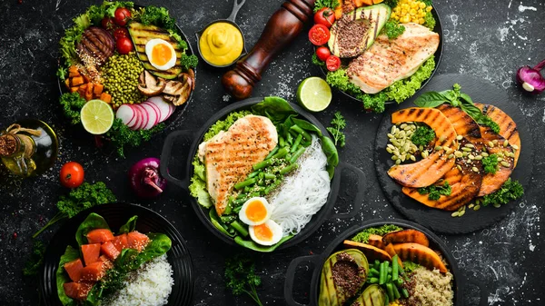 Yemek geçmişi: makarna, tavuk, balkabağı, salata, et, mantar, sebze. Siyah taştan bir arka planda. Üst Manzara. Metin için boş alan.