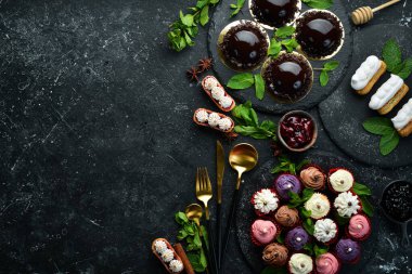 Kahve ve çay için siyah taştan bir arka planda tatlı ve tatlı seti. Üst Manzara. Kırsal biçim.