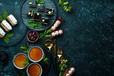 Kahve ve çay için siyah taştan bir arka planda tatlı ve tatlı seti. Üst Manzara. Kırsal biçim.