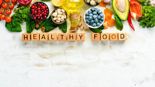 Food background. Healthy food for humans: vegetables, fruits, fish, meat, nuts and greens. on a white wooden background. Top view. Free copy space.