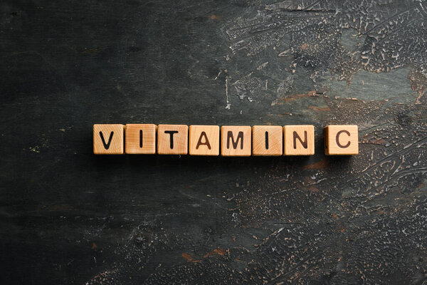 The inscription "VITAMIN C" is laid out of wooden cubes. Top view.
