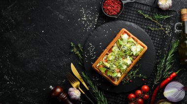Kahvaltıda. Belçika waffleları: avokado, tuzlu balık ve mikroyeşil. Siyah taştan bir tabakta.
