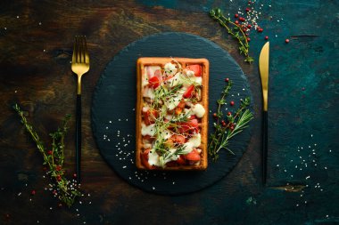 Belçika waffleları: domuz pastırması, domates ve mikroyeşillik. Kahvaltıda. Siyah taştan bir tabakta.