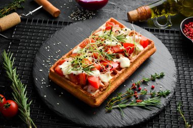 Belçika waffleları: domuz pastırması, domates ve mikroyeşillik. Kahvaltıda. Siyah taştan bir tabakta.