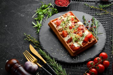 Belçika waffleları: domuz pastırması, domates ve mikroyeşillik. Kahvaltıda. Siyah taştan bir tabakta.