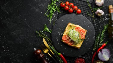 Sandviç. Avokado humuslu taze ciabatta ve tuzlanmış kırmızı balık. Siyah taştan bir tabakta.