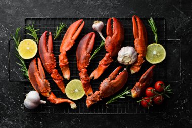 Istakoz pençesi. Kaynamış kabuklu pençeler, siyah taştan bir arka planda. Kırsal biçim.