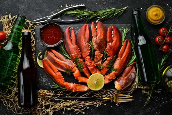 Beer party. Beer, snacks and lobster claws on a black background. Rustic style. Seafood delicacies.