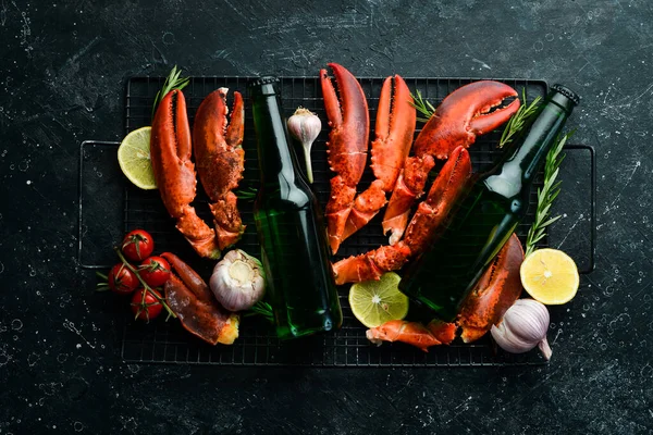 Beer party. Beer, snacks and lobster claws on a black background. Rustic style. Seafood delicacies.