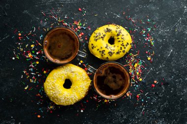 Siyah taştan bir masada bir fincan kahveyle tatlı limon sarısı çörek. Üst görünüm.