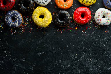 Siyah taşlı arka planda renkli tatlı çörekler. Üst Manzara. Düz Yat.