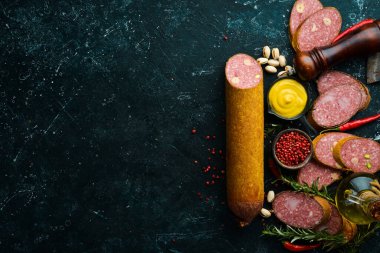 Biberiyeli lezzetli salam ve siyah arka planda baharatlar. Üst Manzara. Kırsal biçim.