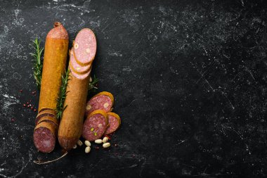 Biberiyeli dilimlenmiş salam ve siyah taş arka planda baharatlar. Üst Manzara. Kırsal biçim.