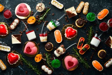 Plastik bardaklarda tatlı mini tatlılar. Siyah taştan bir arka planda. Üst Manzara. Güzel bar..