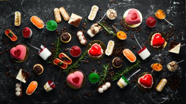 Bir dizi tatlı mini tatlı. Siyah taştan bir arka planda. Üst Manzara. Güzel bar..