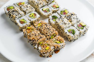 Geleneksel suşi ruloları ve susamlı maki, avokado ve balık. Japon yemeği. Üst Manzara. Beyaz bir arkaplanda.